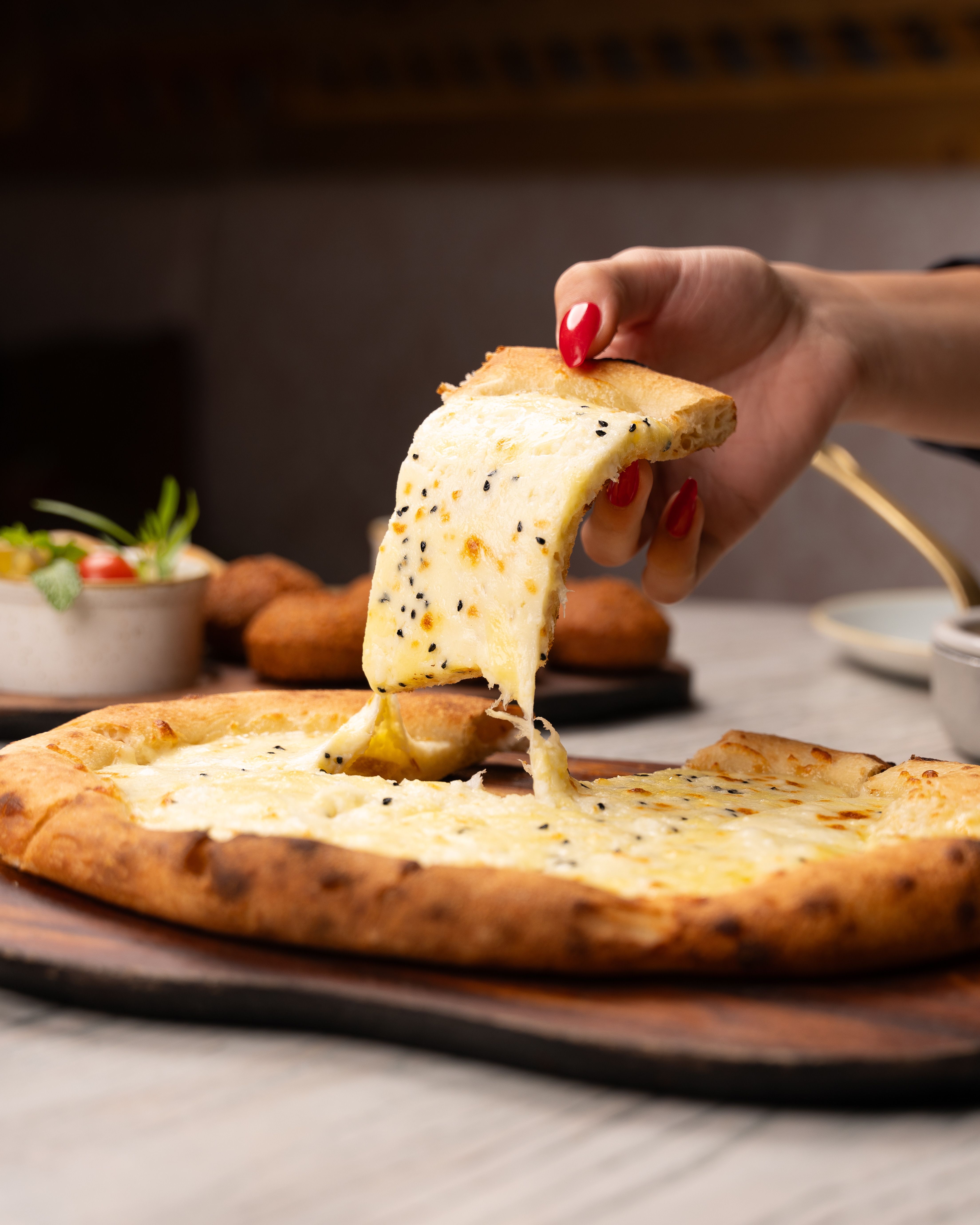 A tempting slice of cheese pizza with melted cheese being lifted by hand.