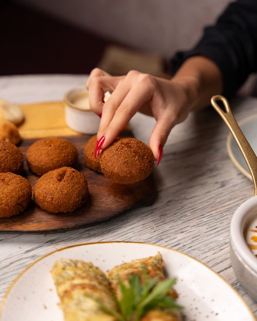 Free Hand reaching for falafel on a mezze platter, perfect for Mediterranean cuisine themes. Stock Photo