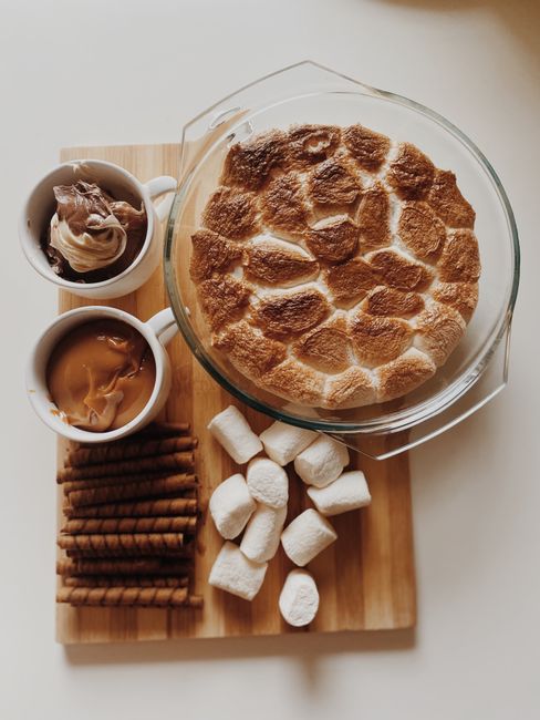 A dozen s'mores muffins in paper liners with golden toasted marshmallow tops and melted chocolate chips visible along the crumb.