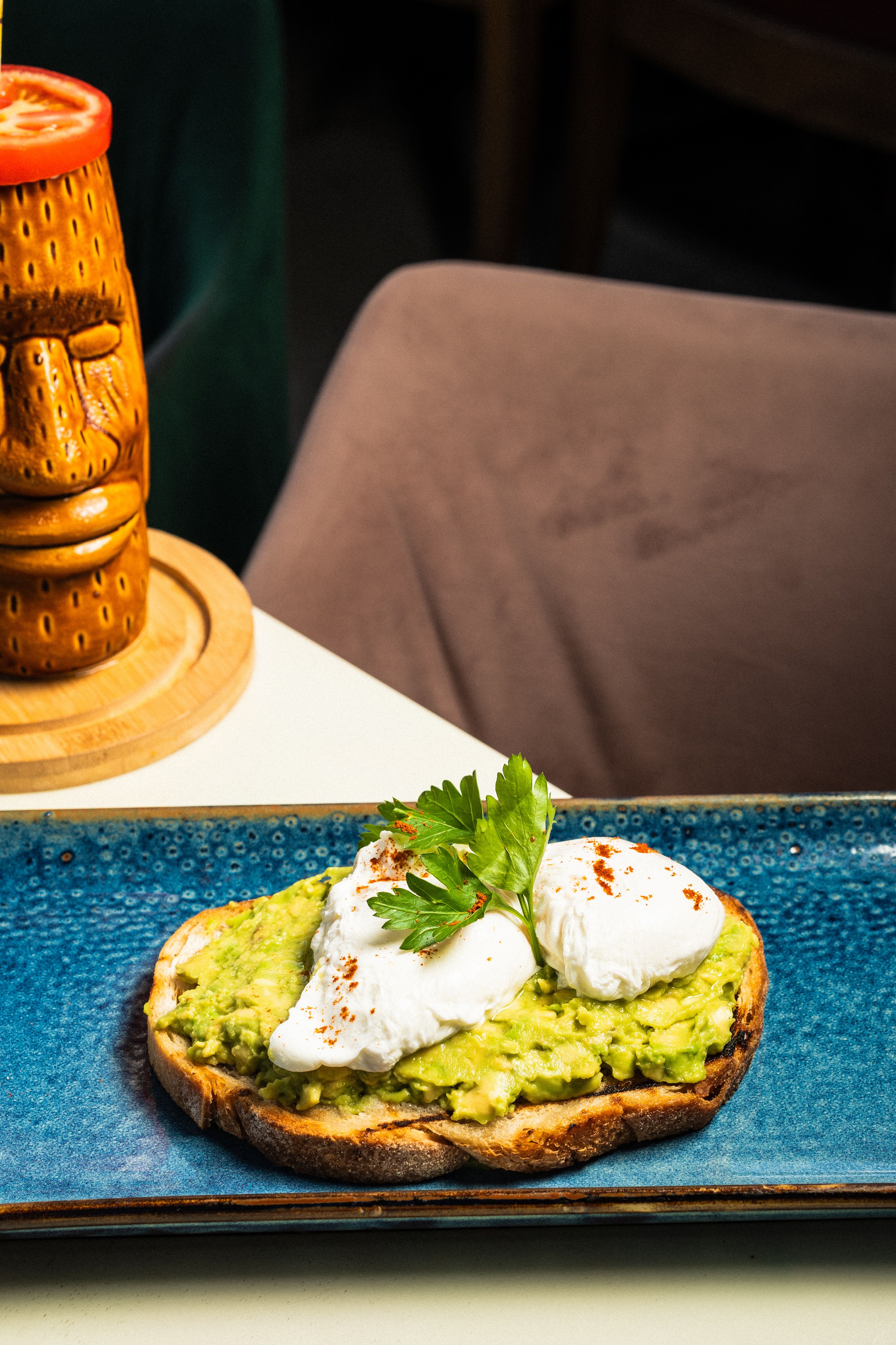 Savor healthy avocado toast with poached eggs at a cozy cafe in England. Perfect breakfast choice.