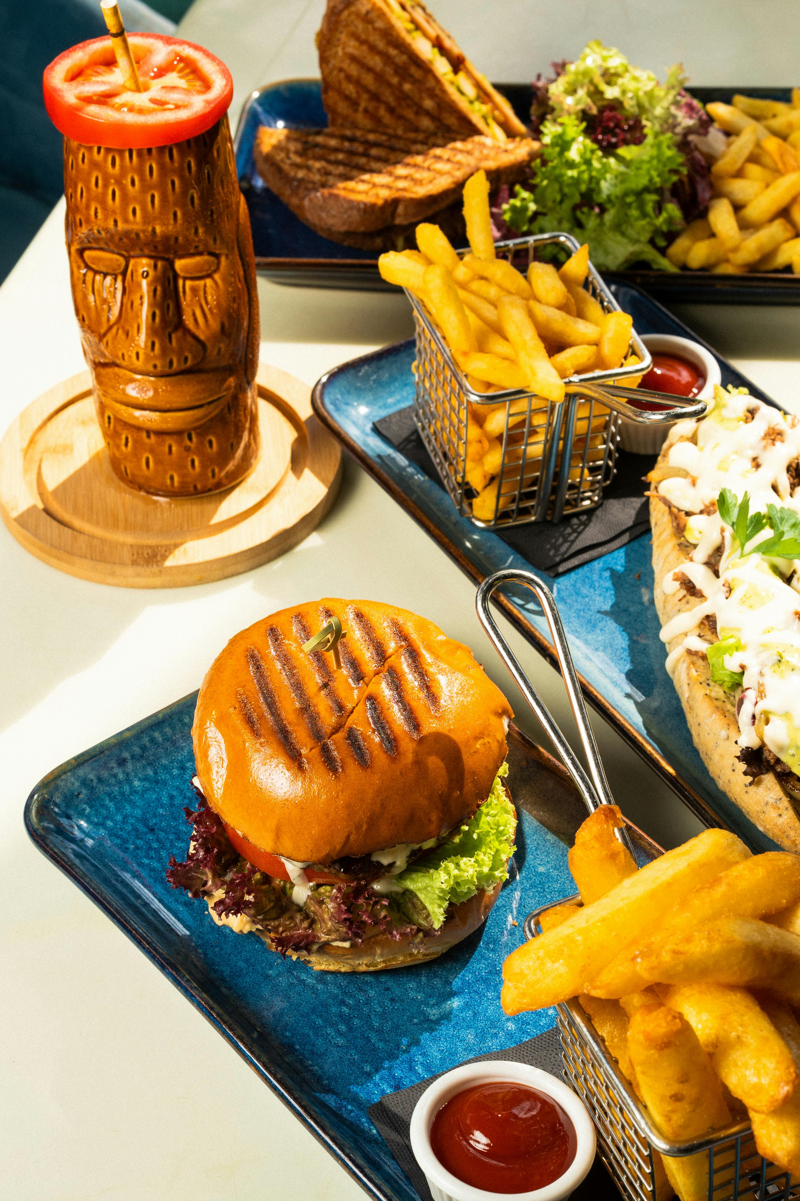 Free A vibrant display of a beef burger, fries, and tiki bar drink, perfect for a casual lunch. Stock Photo