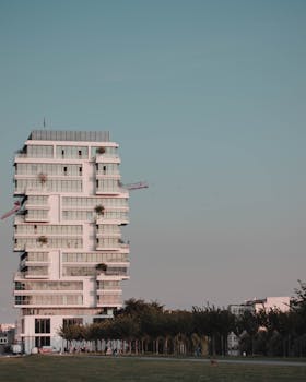 在晴朗的蓝天下，矗立着具有几何设计的当代高层建筑