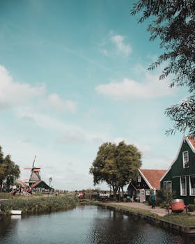 荷兰乡村一条宁静的河流旁，风景如画，矗立着传统的风车
