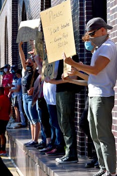 Group of people wearing masks and holding protest signs during a demonstration.