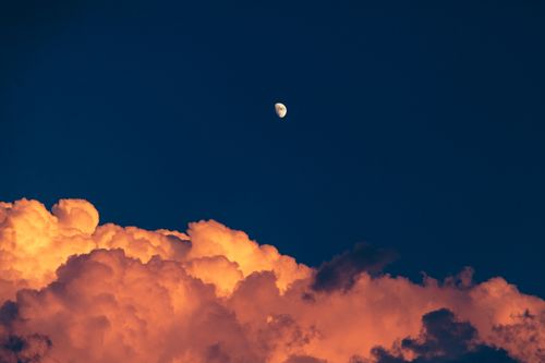 Free Capture of the moon rising over dramatic red clouds during a vibrant sunset. Stock Photo