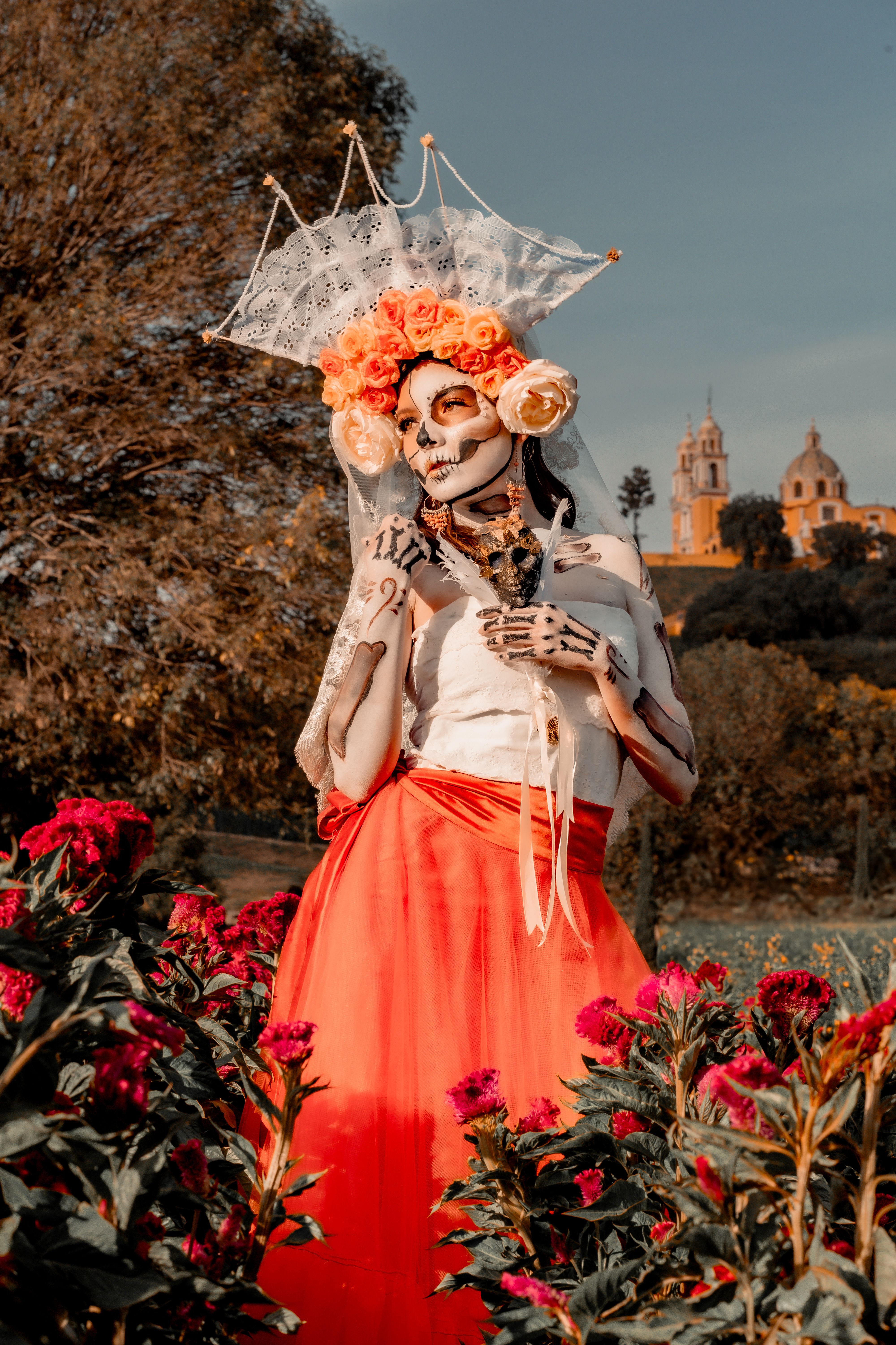 Woman in Day of the Dead costume amidst flowers in Cholula, Mexico.