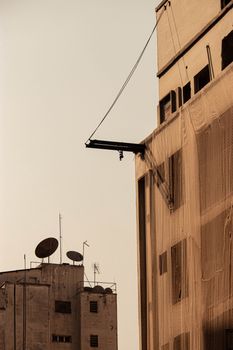 A cityscape with old buildings and satellite dishes captured at sunset, creating a warm ambiance.