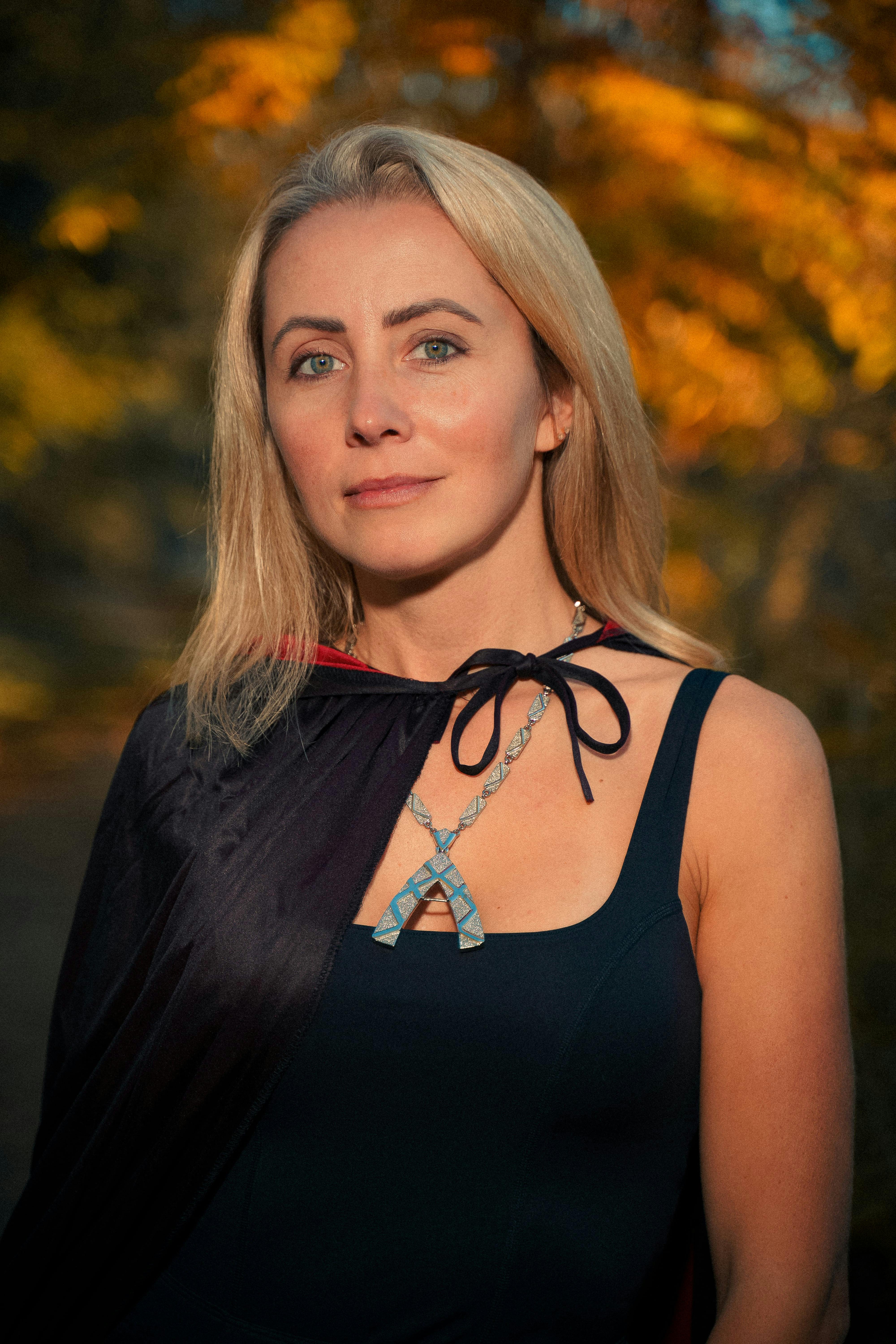 Blonde woman in a Halloween cape with autumn background.