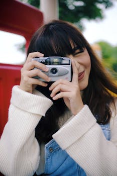 一位年轻女子在户外用复古胶片相机微笑着捕捉片刻