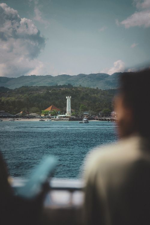 Free Stunning harbor view in Bali featuring a lighthouse and mountains in the background. Stock Photo