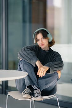 Casual portrait of a woman wearing headphones, seated in a modern interior.