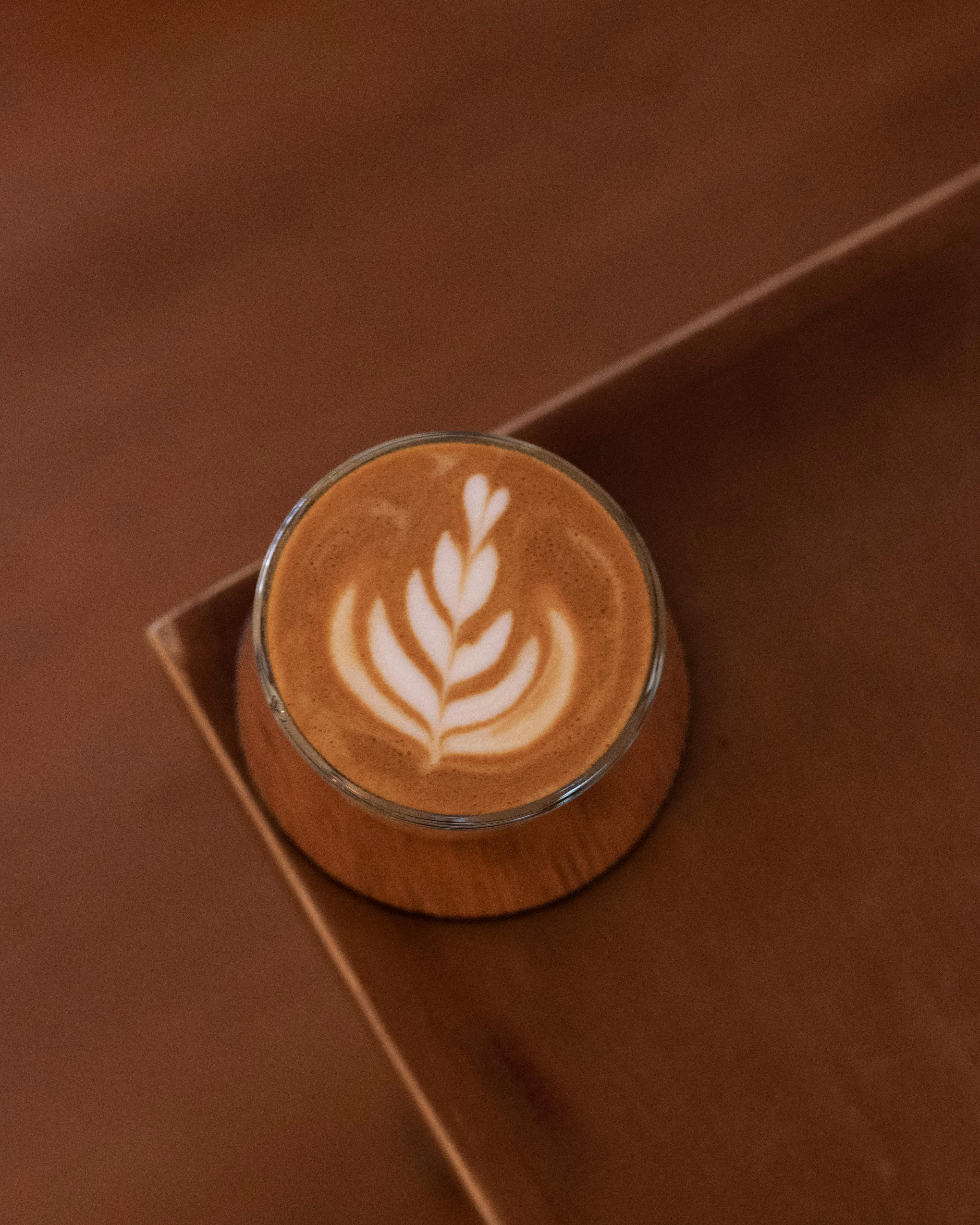 Top-down latte art in glass on warm tabletop.
