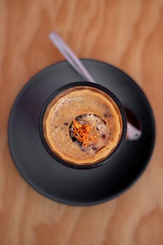 Top view of a flavorful black coffee cup with orange zest on modern table setting.