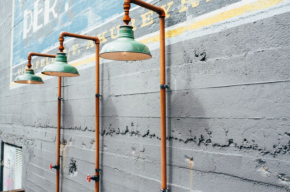 Outdoor vintage lamps with copper piping against a textured concrete wall, urban design