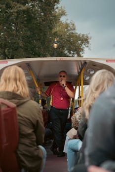 Tour guide engaging visitors on an open-top bus tour in London, UK.
