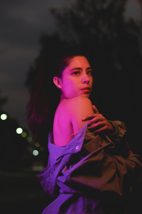 Free Artistic portrait of a young woman with vibrant lighting at night. Stock Photo