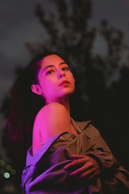 Free Moody portrait of a woman under vibrant neon lights, creating a dramatic effect. Stock Photo