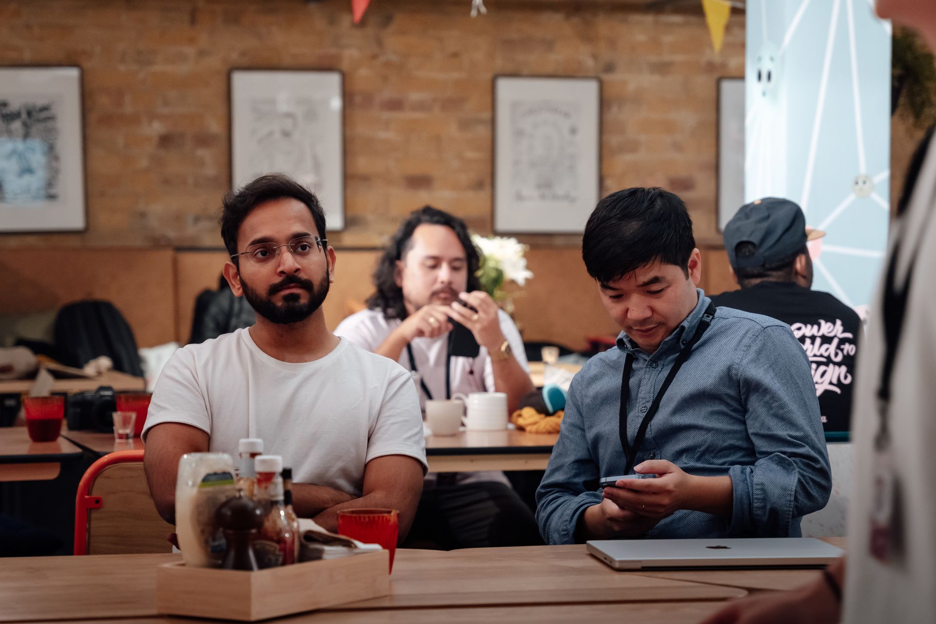 Men casually chatting and using devices in a cozy London café setting.