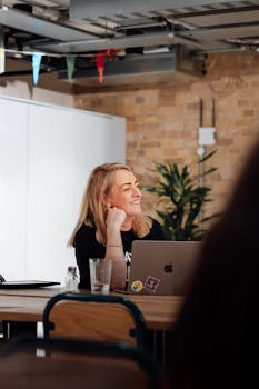 Blonde woman smiling while sitting at a desk in a modern office in London, UK.