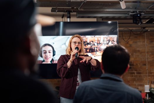 A woman presents using a microphone in a London event space.