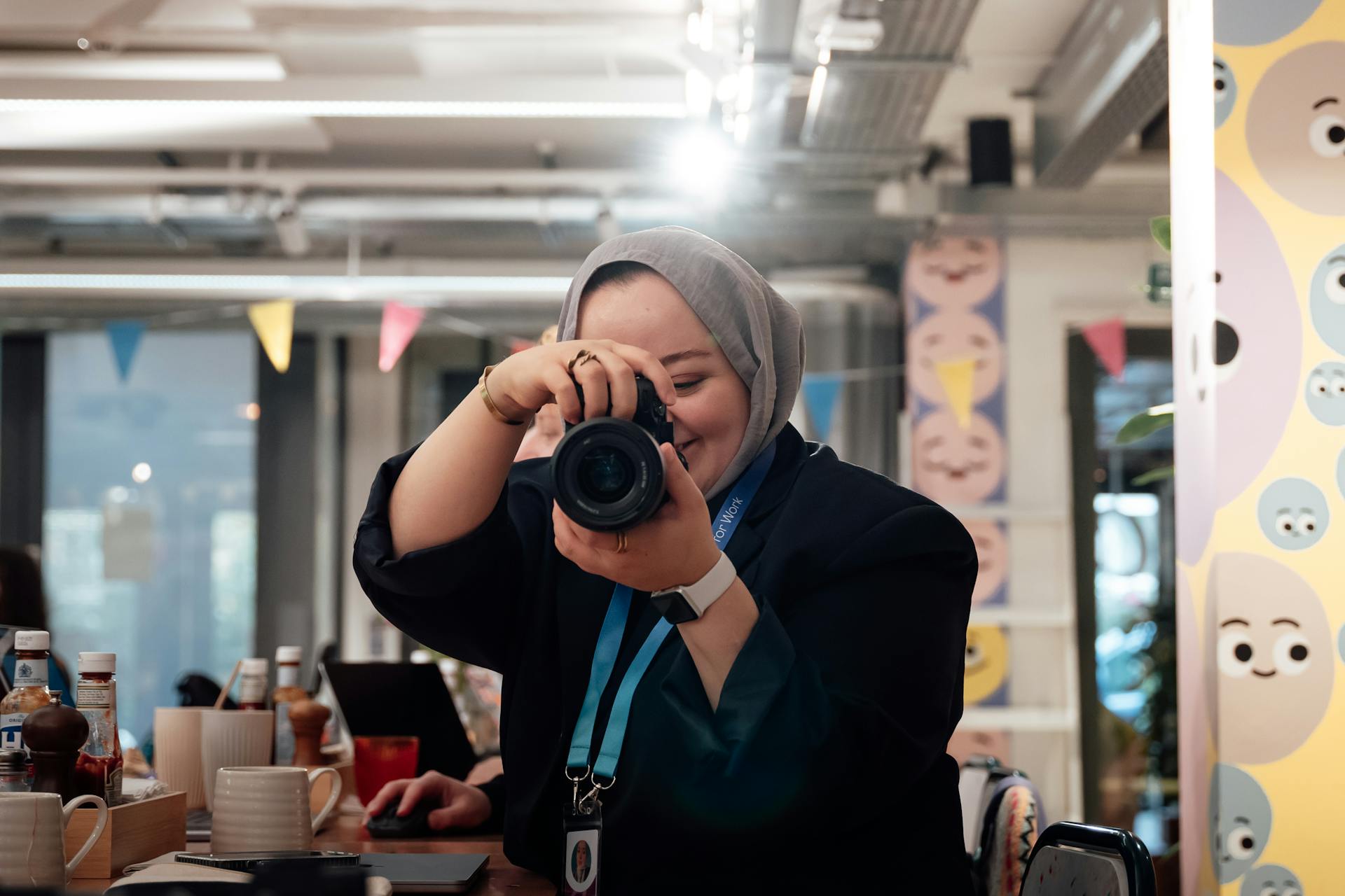 Portrait of a person taking a photo inside a colorful and modern workspace setting.