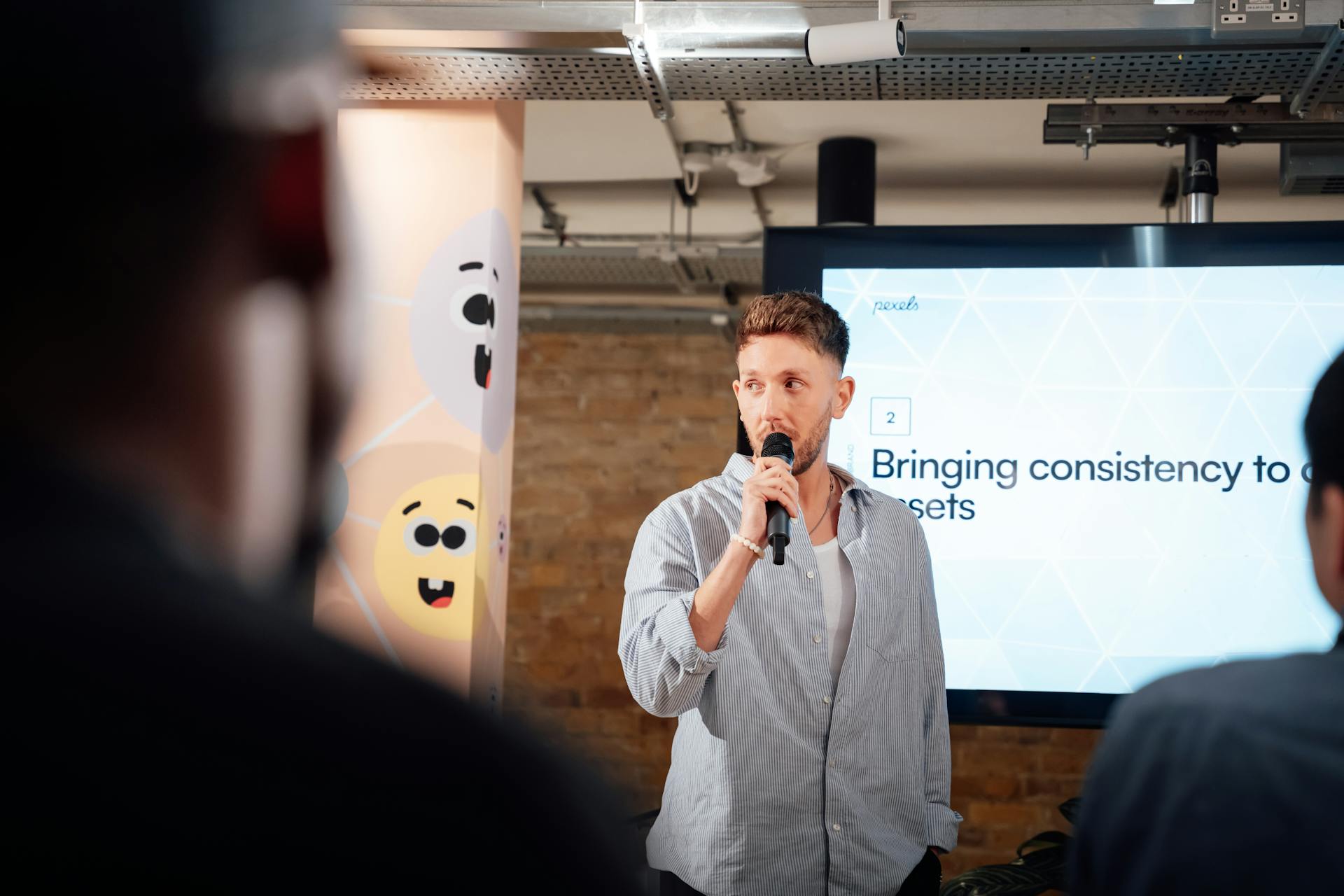 Man presenting with microphone at a business event in London, engaging audience.