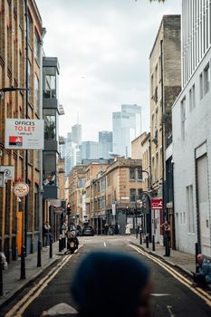 A bustling street scene in London with modern skyscrapers in the background and classic architecture.