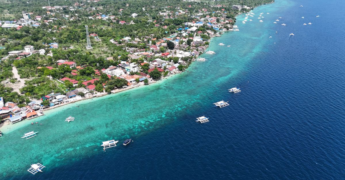 A stunning aerial view of a coastal village, showcasing clear waters and local boats in the Philippines.