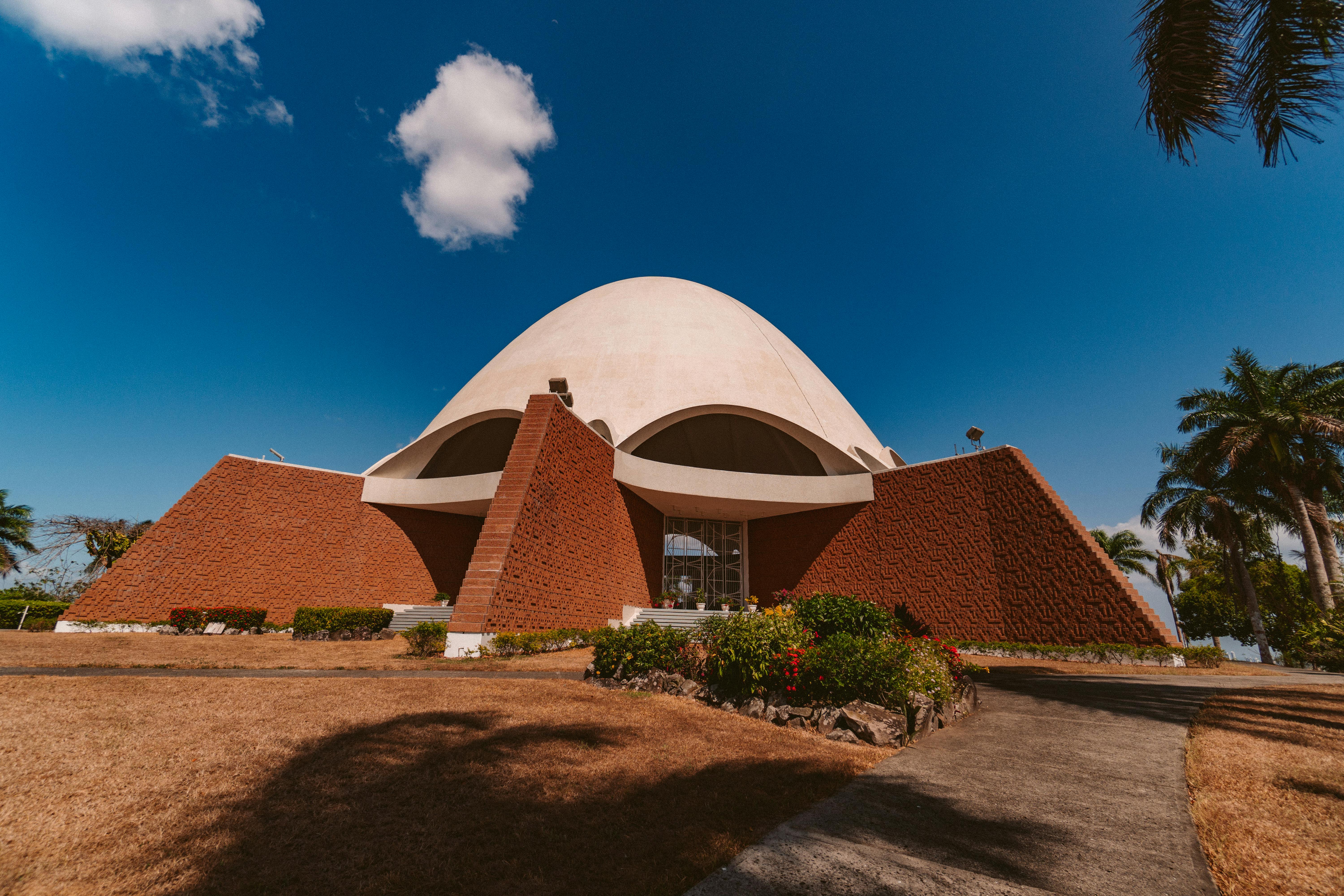 一座拥有圆顶和砖砌立面的现代建筑，矗立在晴朗的蓝天下