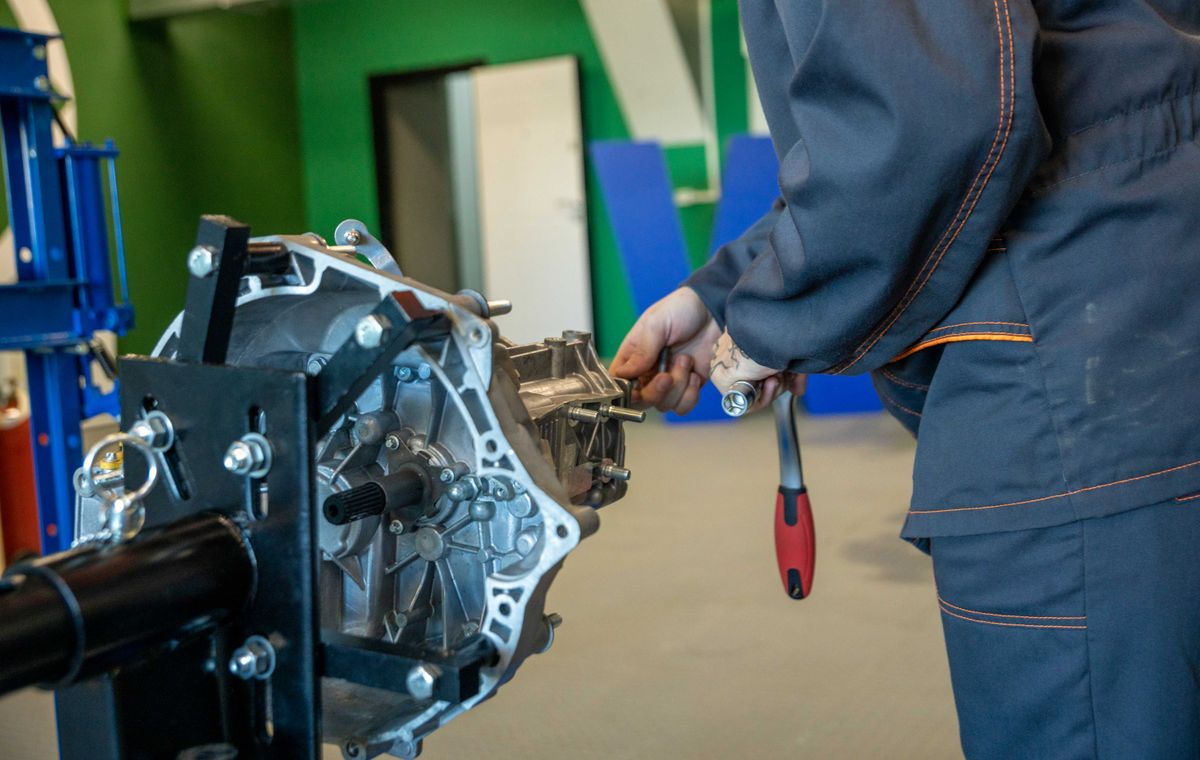 Mechanic repairing a vehicle transmission in a workshop
