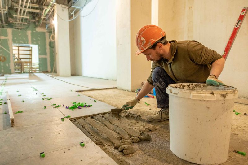 Tiler laying tiles with adhesive and spacers during a renovation project