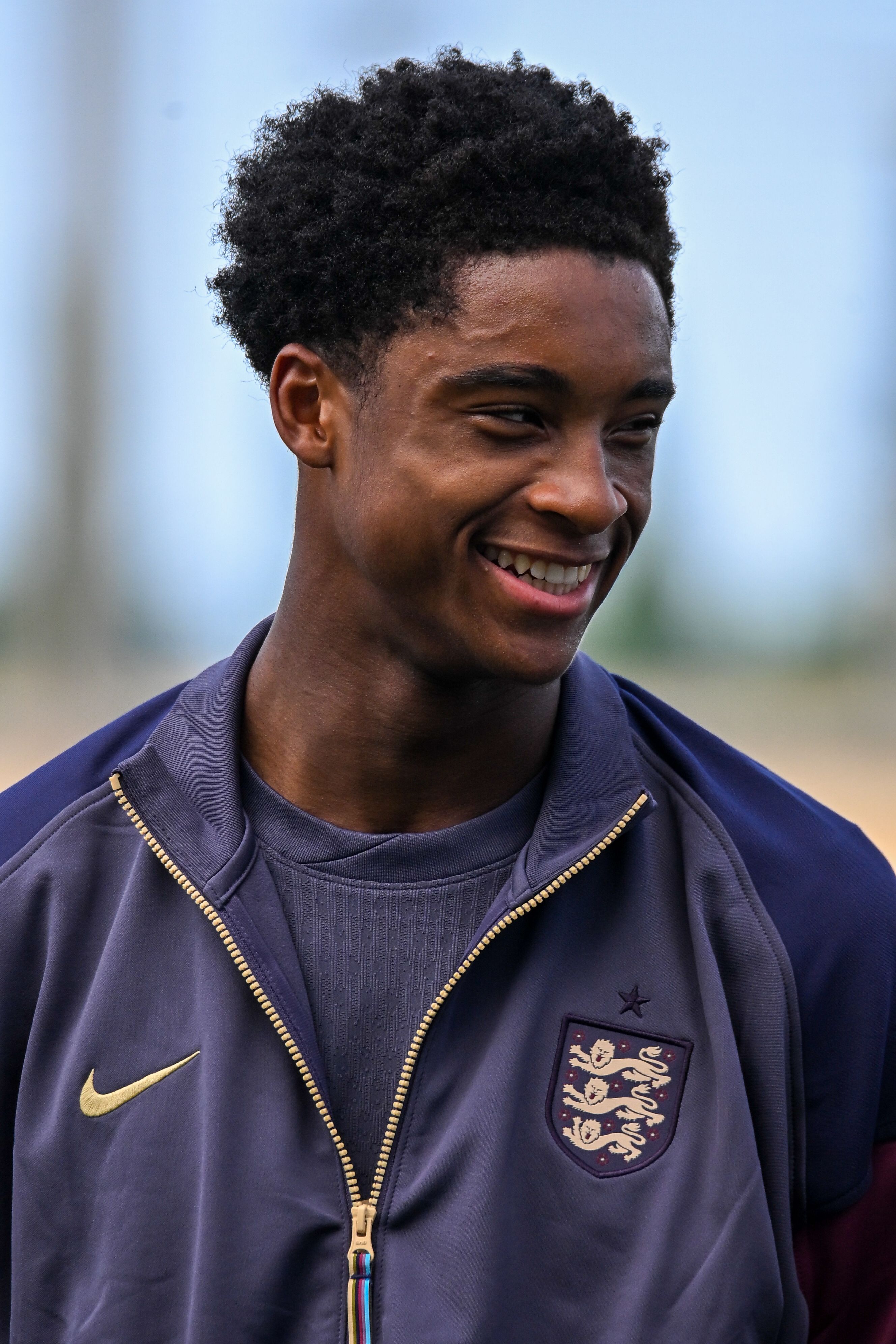 Young man smiling while wearing a sports jacket outdoors.