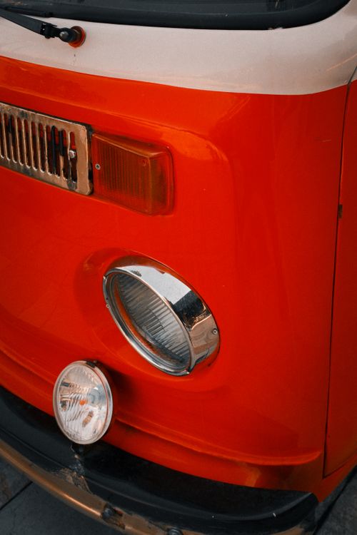 Free Detailed image of retro orange camper van's front detailing, emitting a nostalgic vibe. Stock Photo