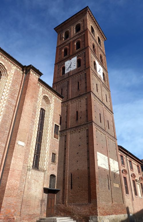Free Majestic brick clock tower under blue sky in Asti, Piedmont, Italy. Stock Photo