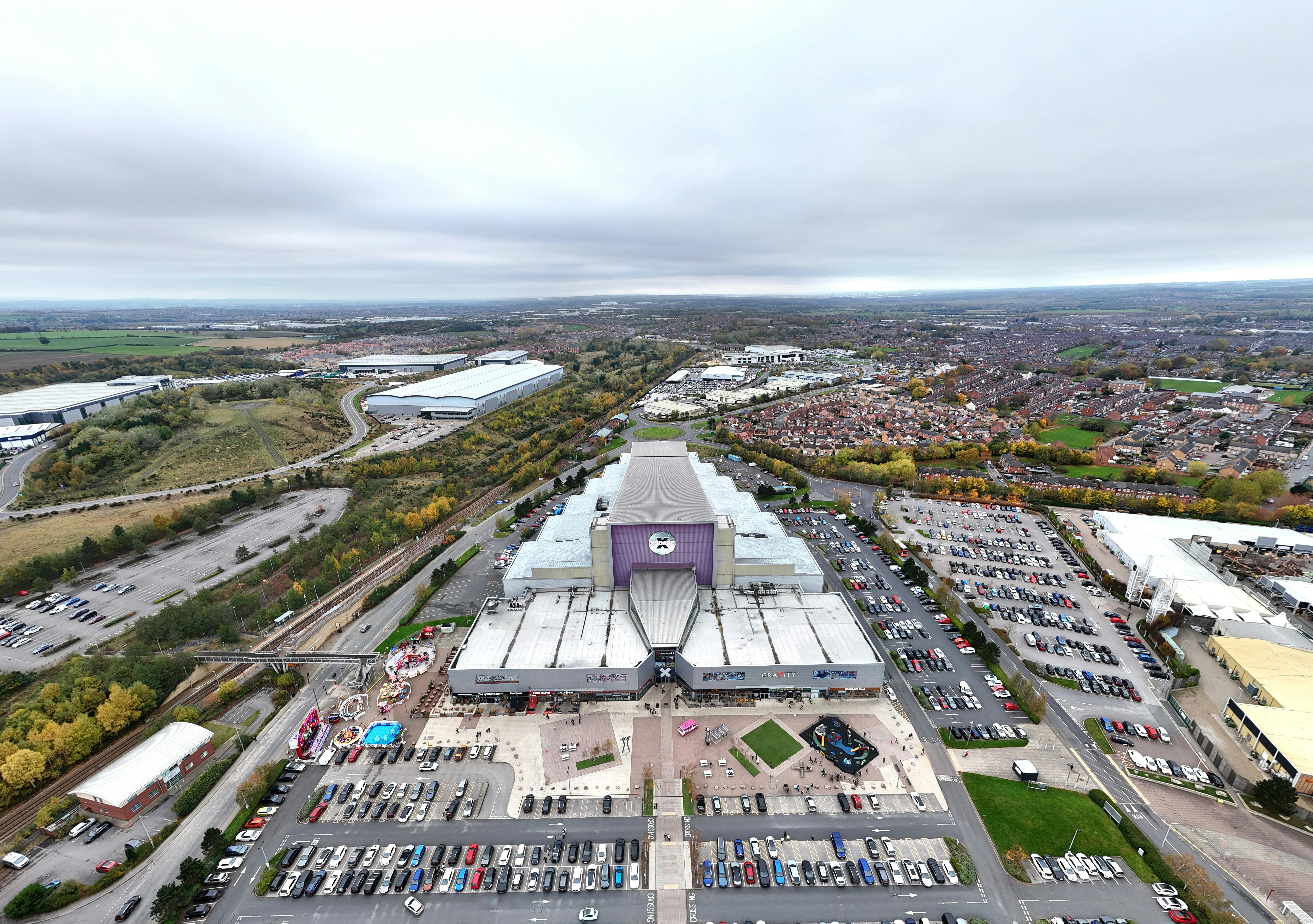 Wide aerial view of a shopping complex surrounded by residential areas and parking lots in Wakefield, UK.