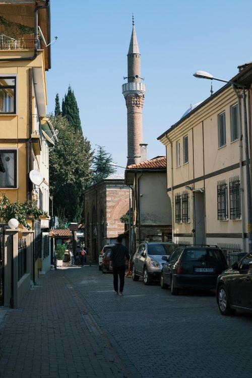 Free A picturesque street with cars and a historical minaret under a clear blue sky. Stock Photo