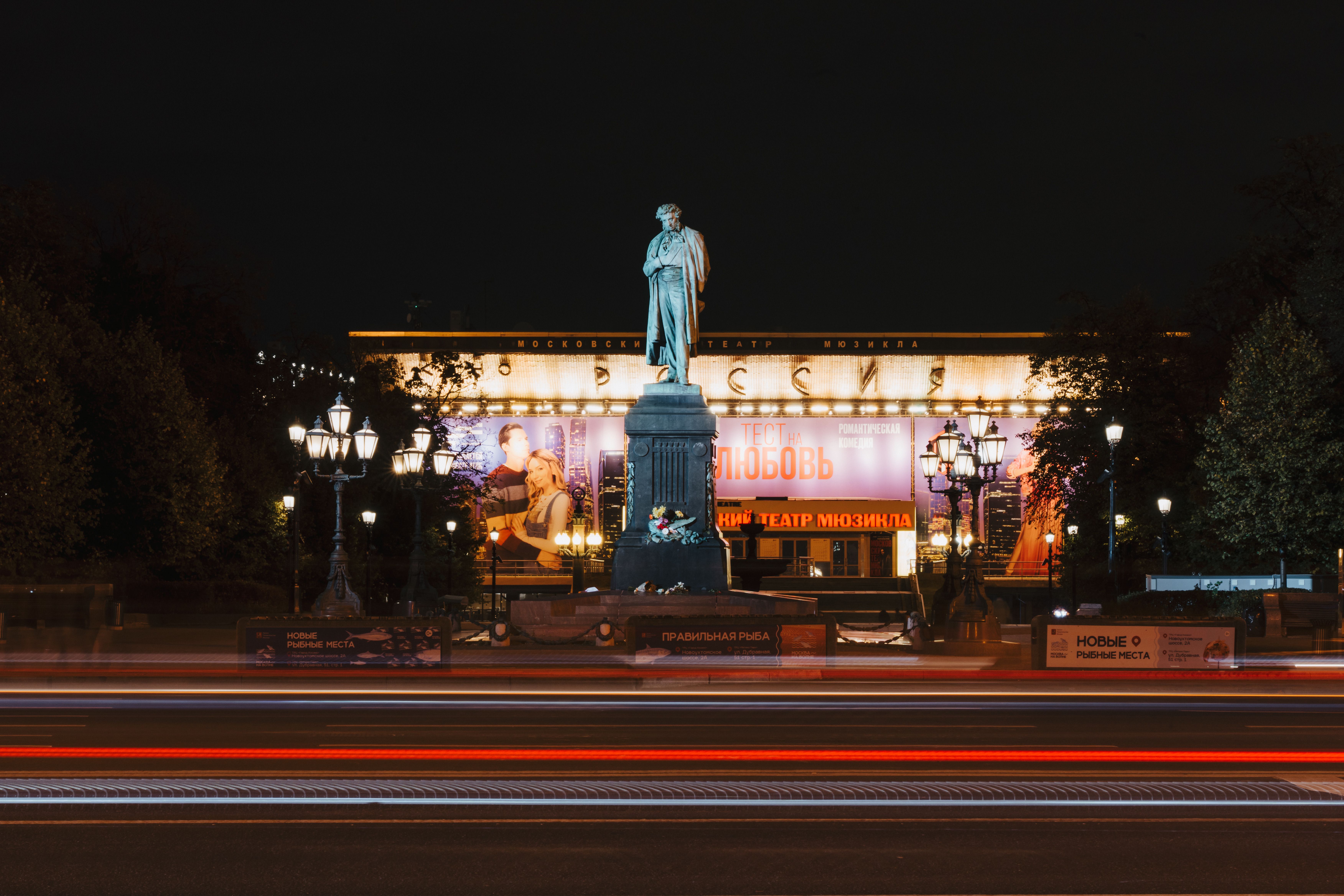 Illuminated monument and theater with streaking lights in Moscow at night.