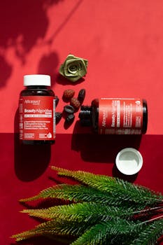 Colorful flat lay of beauty supplements and decor on vibrant red background.