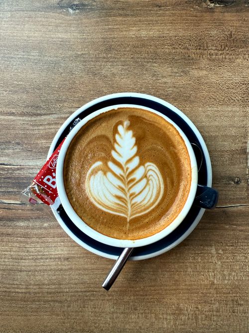 Free Top view of a latte with beautiful art and a biscuit on a wooden table in Interlaken, Switzerland. Stock Photo