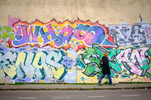 Free Colorful graffiti mural with a person walking by on a street in Bristol, UK. Stock Photo