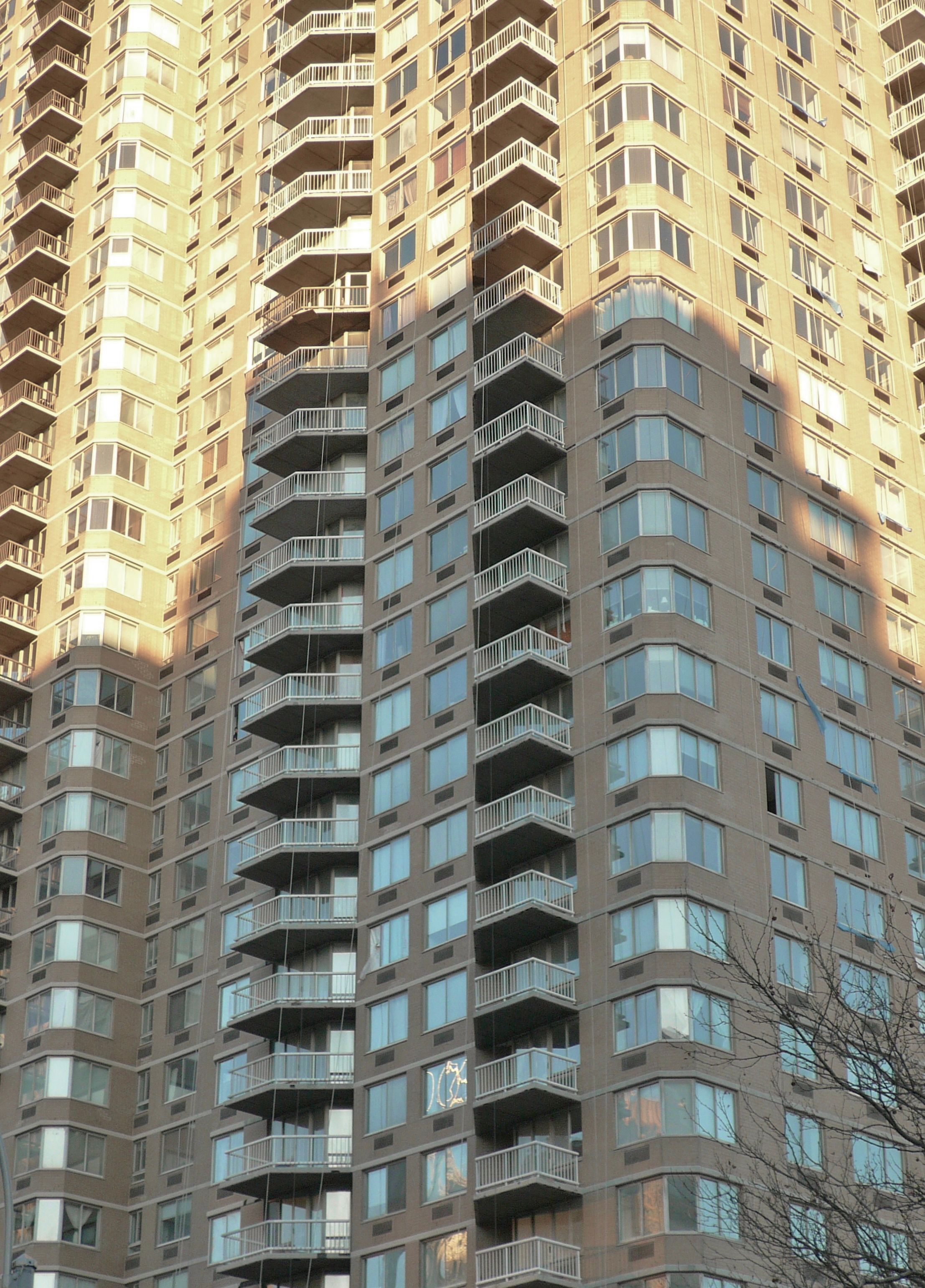 A modern high-rise residential apartment tower with geometric balconies in New York City, representative of Manhattan rental housing