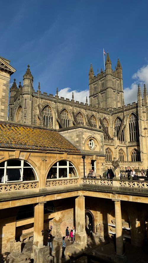 Free Capture of Bath Abbey against a clear blue sky with the historic Roman Baths in the foreground. Stock Photo