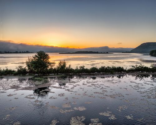 Free Serene sunrise over a tranquil lake with reflections and gentle ripples. Stock Photo
