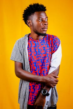 Portrait of a man in a colorful shirt posing against a vibrant yellow background in a studio setting.