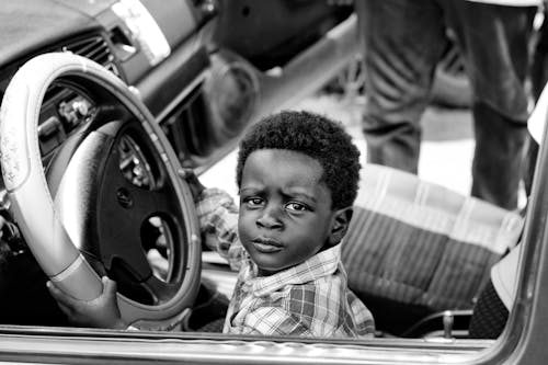 Grayscale Photo of Boy Riding Car