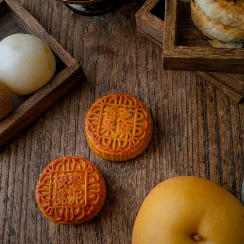 Traditional mooncakes served with a Chinese tea set on a wooden table