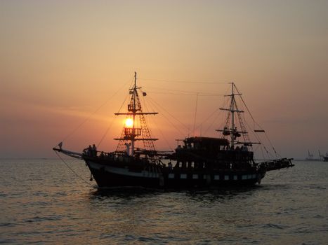 A majestic sailing ship silhouetted against a stunning ocean sunset.