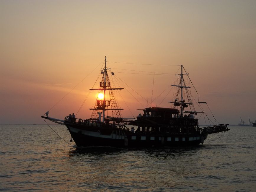 A majestic sailing ship silhouetted against a stunning ocean sunset.