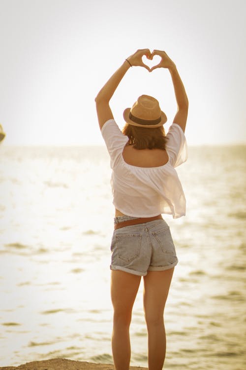 Donna In Piedi Sulla Spiaggia Che Mostra Il Segno Del Cuore