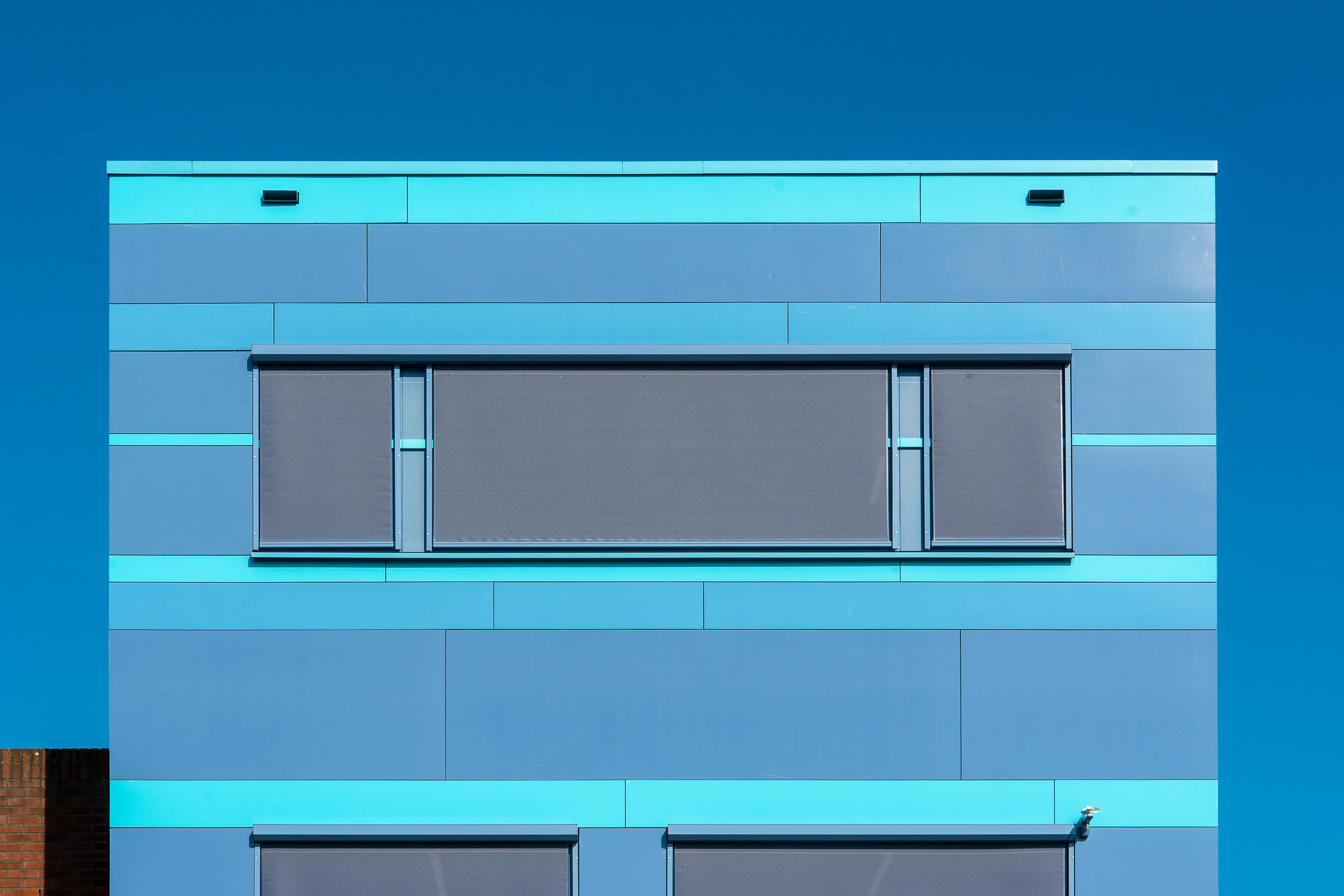 Kostnadsfria Livlig blå modern byggnadsfasad med solskydd mot en klar himmel. Stock foto